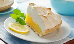 Kawałek cytrynowej tarty z bezą, która nie opadła w piekarniku. Udekorowana plasterkiem cytryny i miętą.
