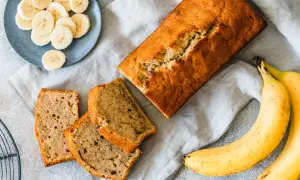 Pyszny chlebek bananowy moje wypieki, pokrojony w kromki, obok świeże banany i talerzyk z plasterkami.