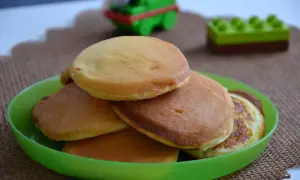 Puszyste pancakes na maślance, idealne na śniadanie. Na zielonym talerzyku, w tle zabawki.