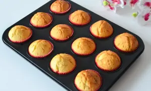 Upieczone, wilgotne muffinki jogurtowe w czerwonych papilotkach, gotowe do jedzenia.