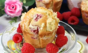Pyszne muffinki z malinami, posypane kruszonką, otoczone świeżymi malinami.