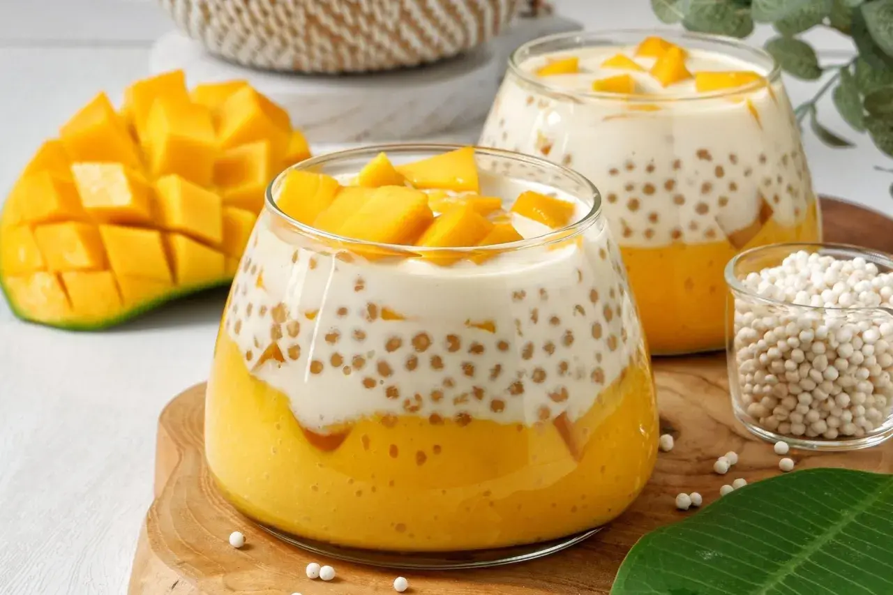 Pyszna tapioka z mango w deserze, z kawałkami owoców i mlekiem kokosowym. Obok świeże mango i nasiona tapioki.