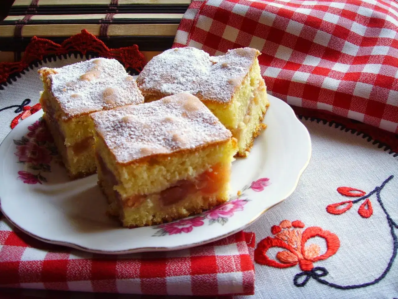 Pyszna szarlotka na talerzu, posypana cukrem pudrem. Czy szarlotkę można piec z termoobiegiem? Tak, i wychodzi równie pyszna!